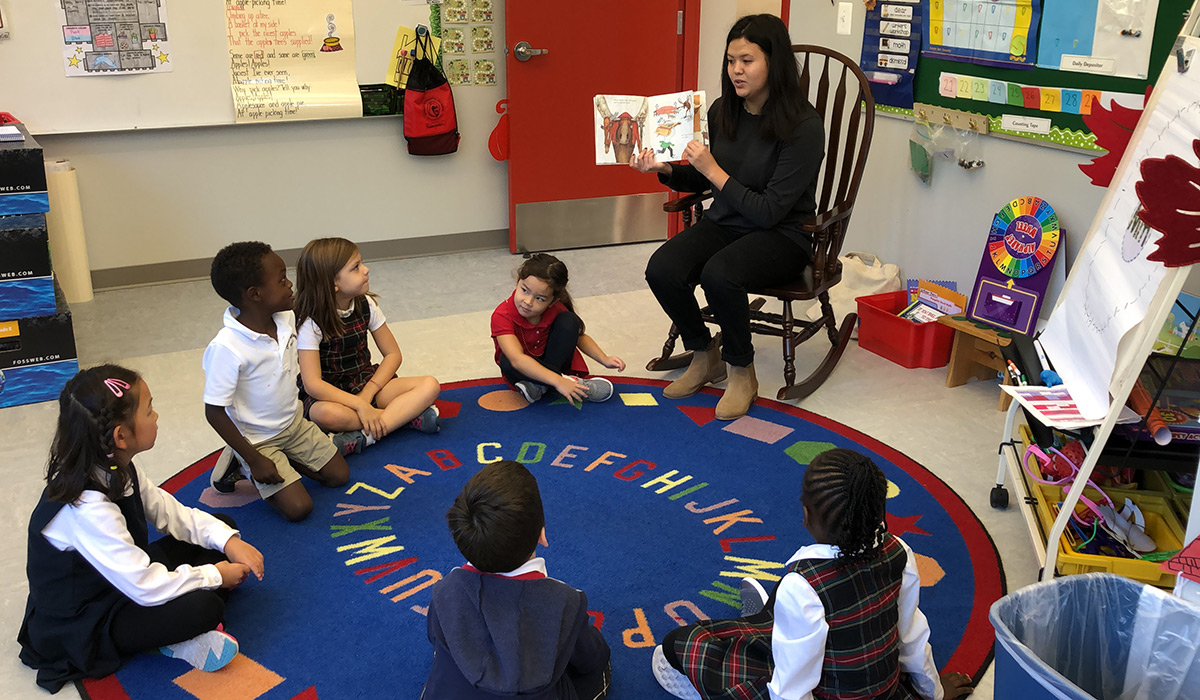 Female student teacher reading to a room of students