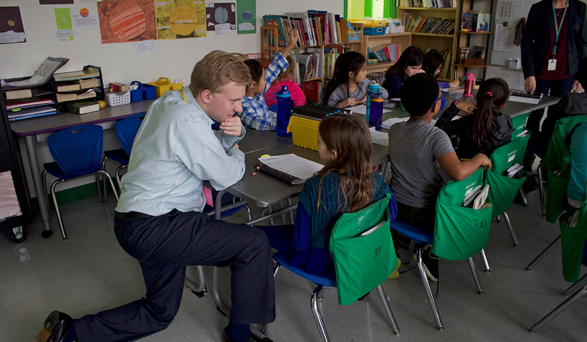 Male Teacher kneeling by students